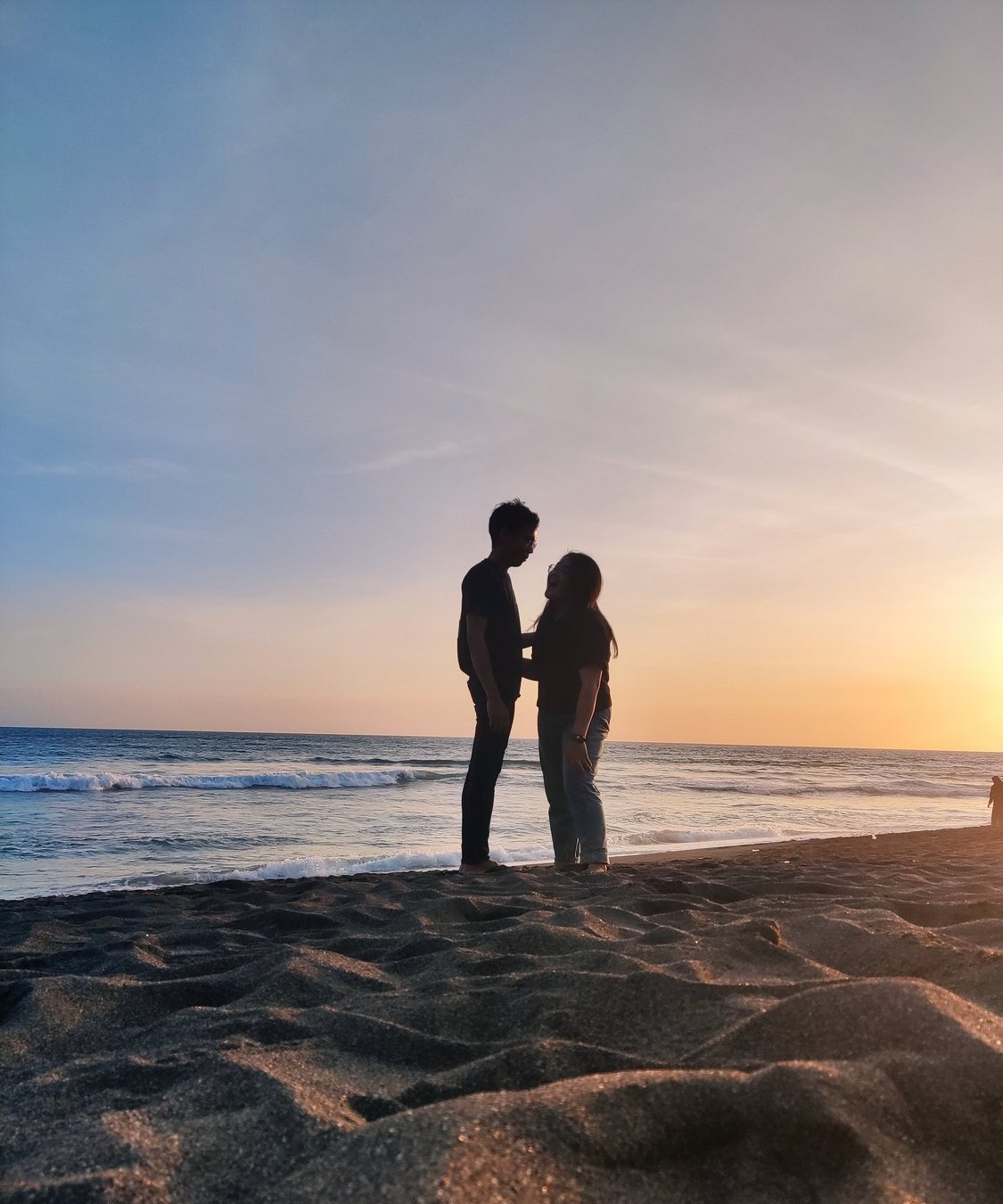 Siluet Hasian dan pasangan di pantai saat matahari terbenam